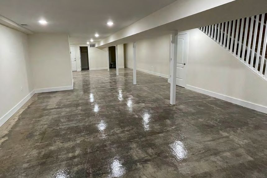 The same kind of empty room before it was finished, with a bare concrete floor reflecting the overhead lights.
